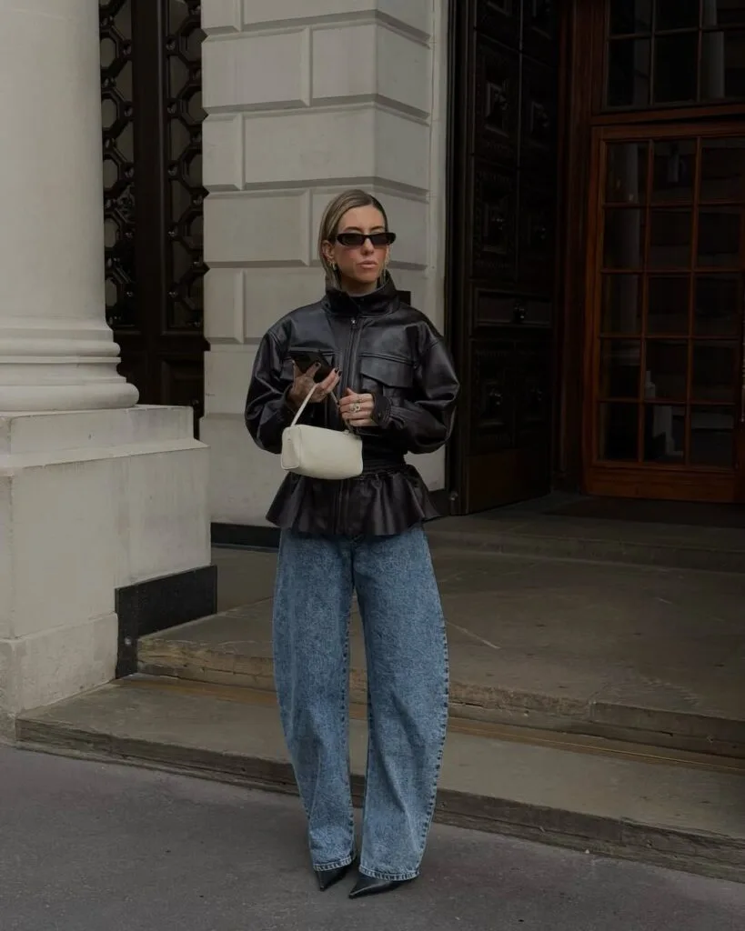 Woman in a black leather peplum jacket and wide-leg jeans in a fall 2026 outfit.
