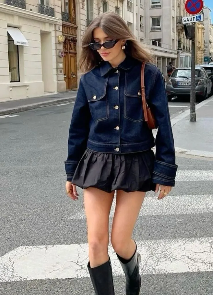 Woman in a denim peplum jacket, black mini skirt, and knee-high boots for a fall outfit.