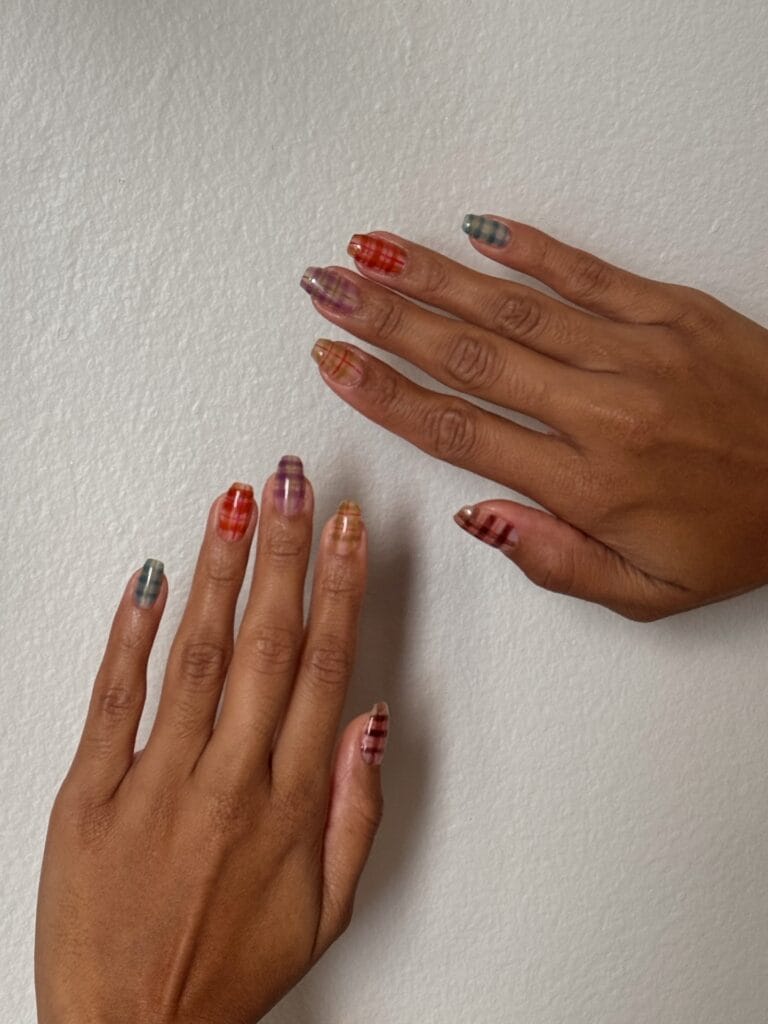 Short round autumn nail trends in sheer plaid, soft coral, plum, amber and teal on a nude base