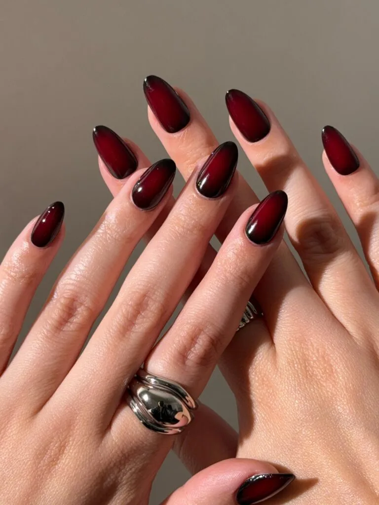 Black cherry fall aura nails with bright red centers, dark edges, and glossy almond shapes.