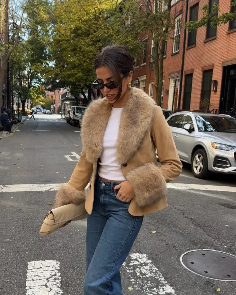 Tan jacket with a fuzzy collar and cuffs, jeans, and a white top in an autumn outfit.