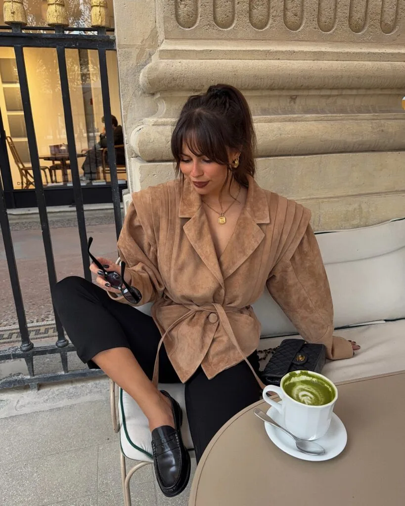 Fall outfit with tan suede jacket, black capri pants, black loafers, and quilted black bag.