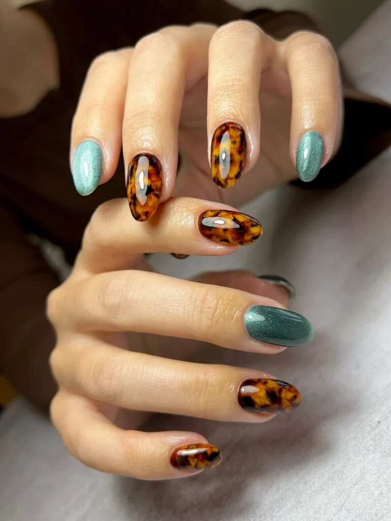 Tortoise nails paired with glossy amber-brown pattern and muted teal shimmer accent nails.
