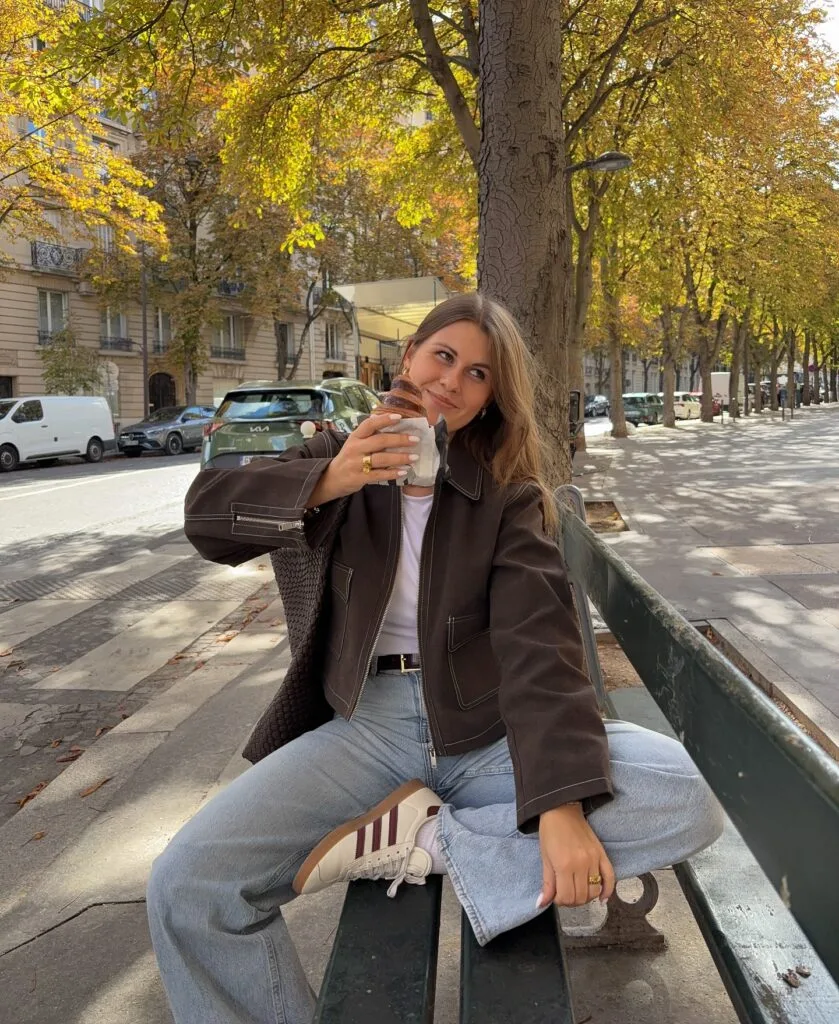 Fall outfit with brown leather jacket, white tee, straight-leg jeans, and sneakers.