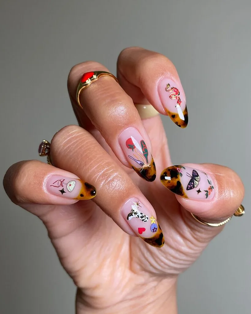Almond tortoiseshell French tips with sheer pink nails and colorful tiny illustrated nail art.
