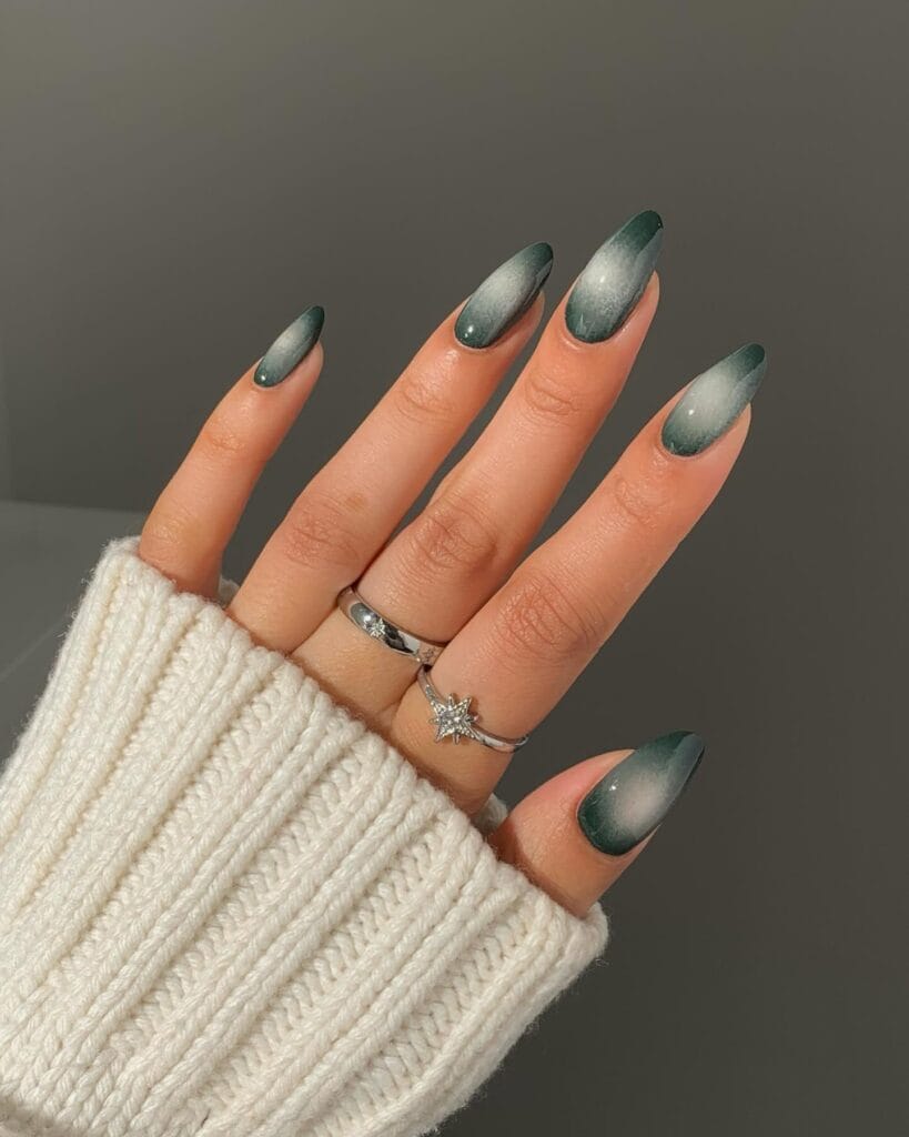 Forest green fall aura nails with pale smoky centers and glossy almond shapes.
