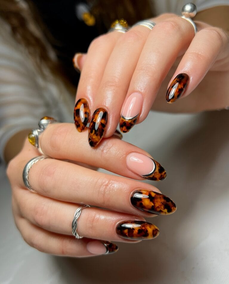 Almond tortoiseshell nails with French tips, sheer pink bases and thin metallic silver outlines.