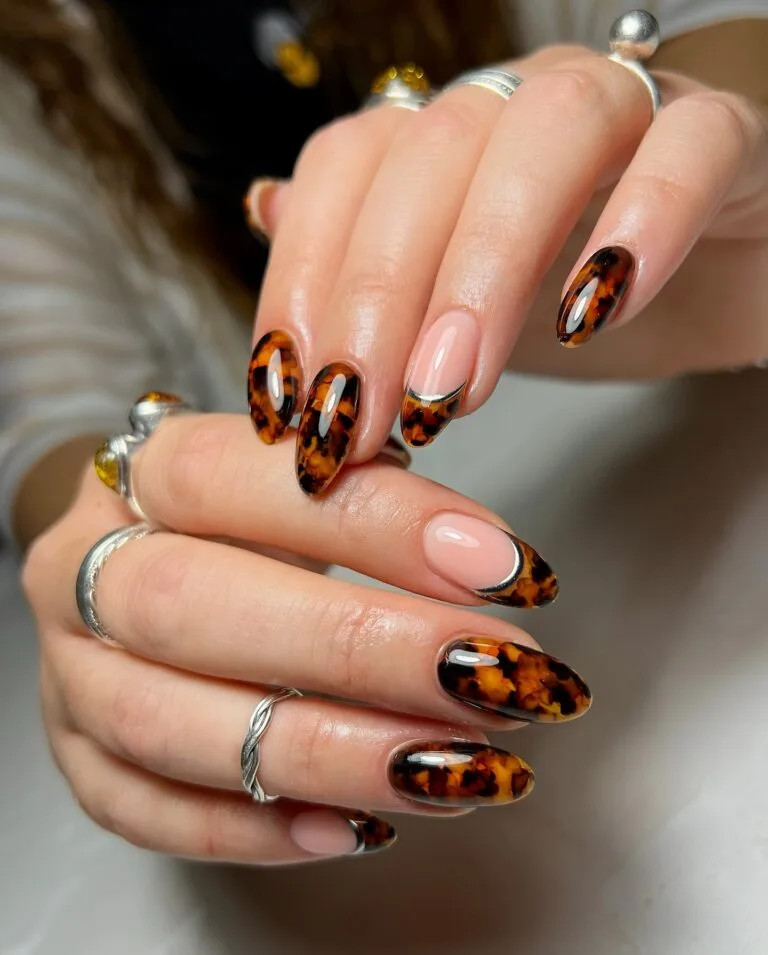Almond tortoiseshell nails with French tips, sheer pink bases and thin metallic silver outlines.