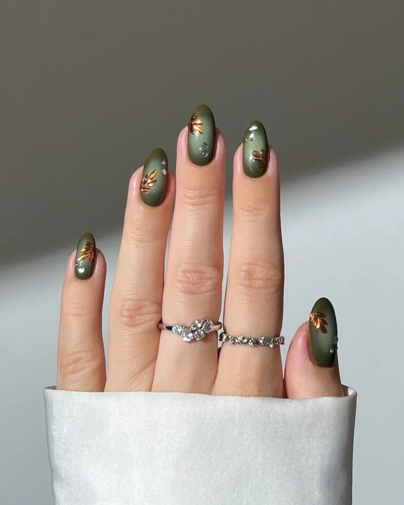 Olive fall aura nails with darker edges, copper leaf accents, and tiny clear droplets.