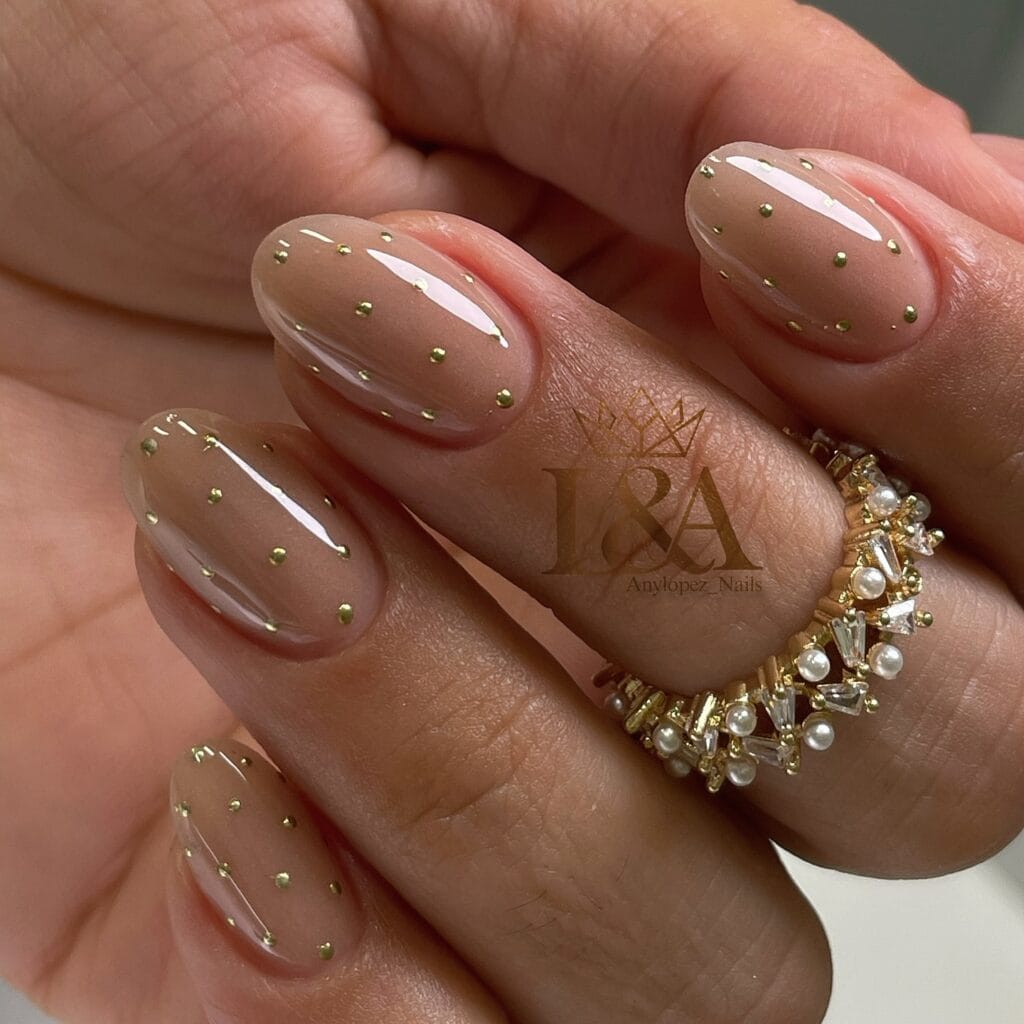 Sheer nude oval nails with scattered gold dots 