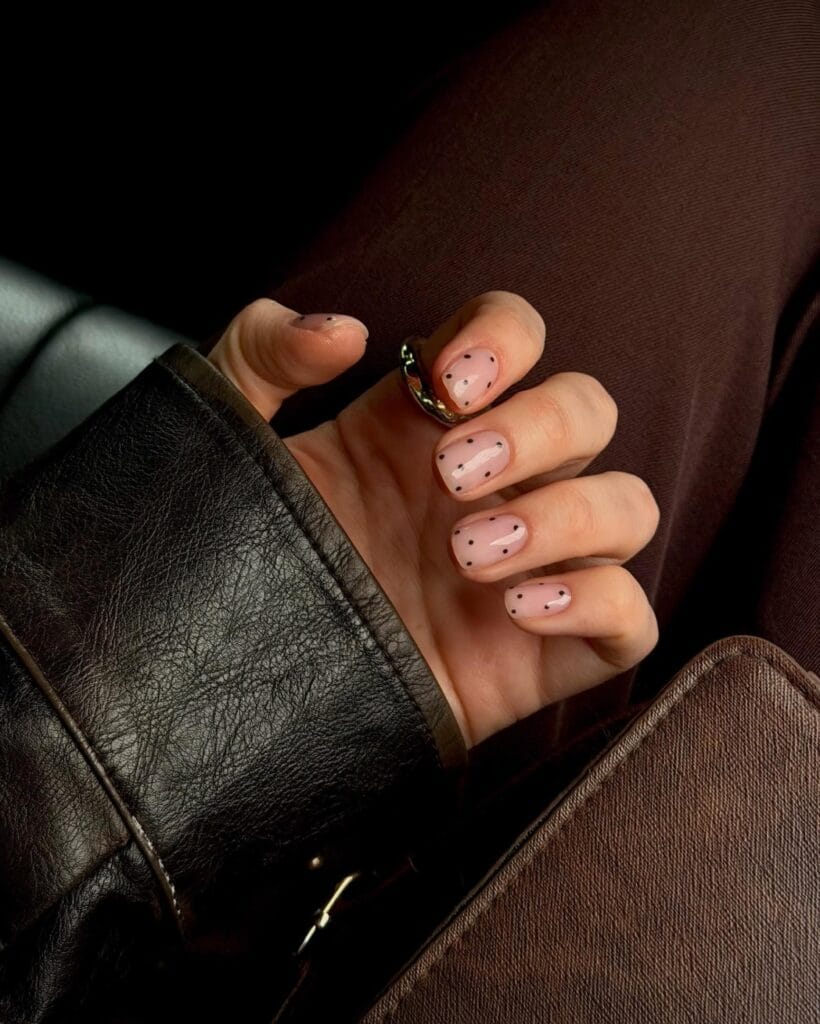 Short milky pink autumn nails with tiny brown dots and loose white brushstroke accents.