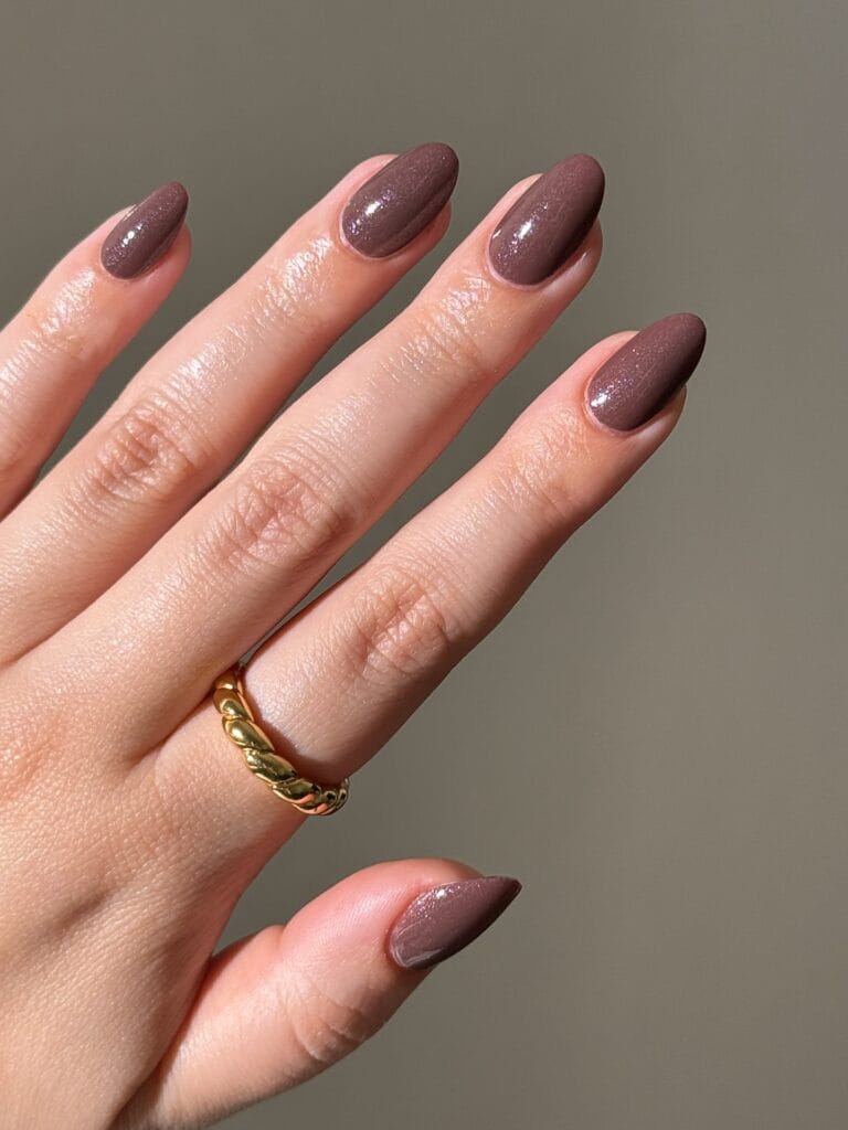 Mauve-brown neutral fall nails with fine shimmer and a glossy almond shape.