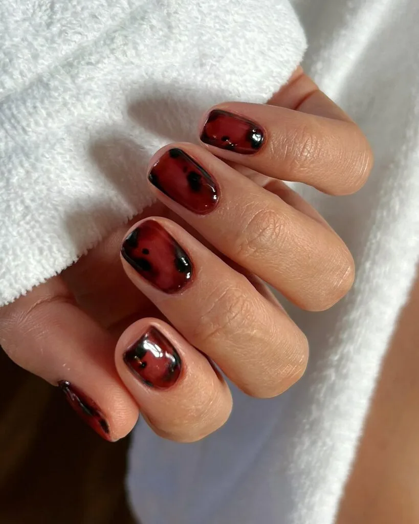 Short square fall nail trends 2026 in deep oxblood jelly with black tortoiseshell blotches
