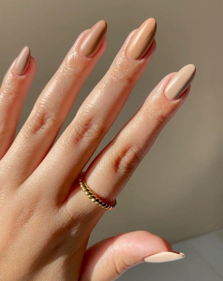 Almond nails in different nude shades including taupe, caramel, beige, and cream.
