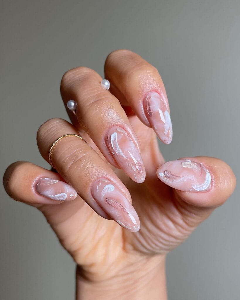 Sheer blush fall nail designs with loose white and soft mauve brushstroke swirls on almond nails.