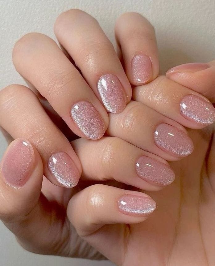 Short pink nude nails with a soft silver cat-eye effect and glossy finish.
