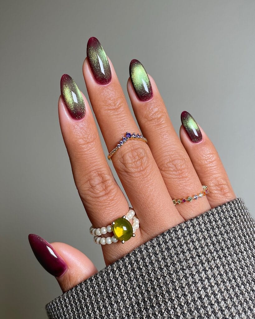 Long almond fall nail trends in burgundy velvet with a gold-green magnetic shimmer band