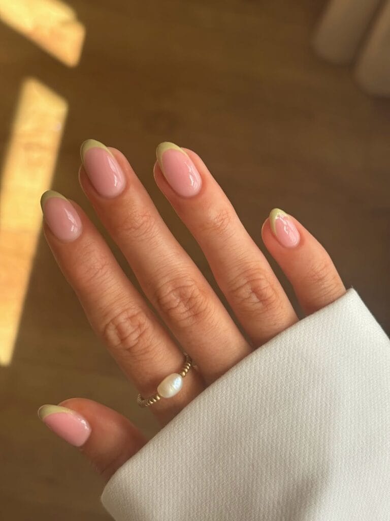Early fall nails with pale pistachio French tips on glossy sheer pink almond nails.