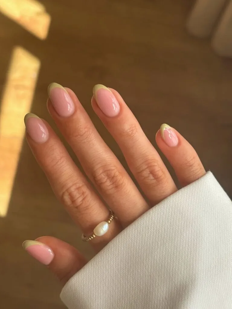 Early fall nails with pale pistachio French tips on glossy sheer pink almond nails.