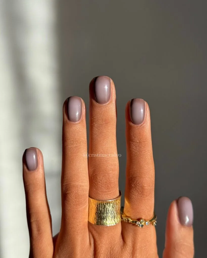 Short taupe fall aura nails with soft dark shading and text “@cristinaccalvo.”