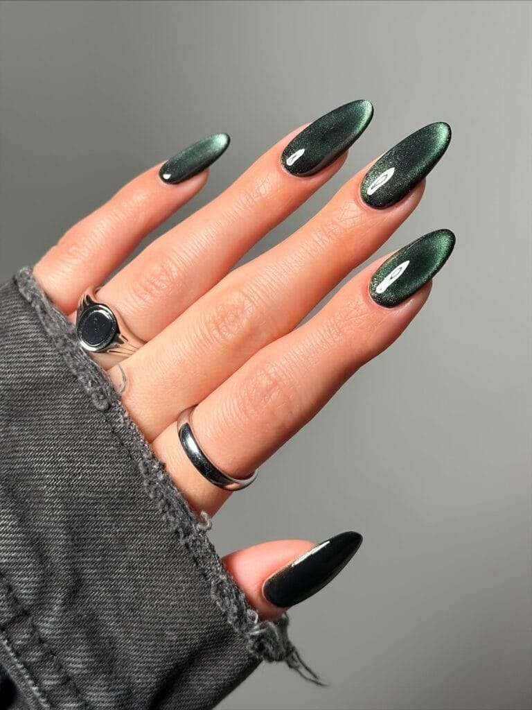 Long almond 2026 autumn nails in deep forest green velvet cat eye with one solid black accent