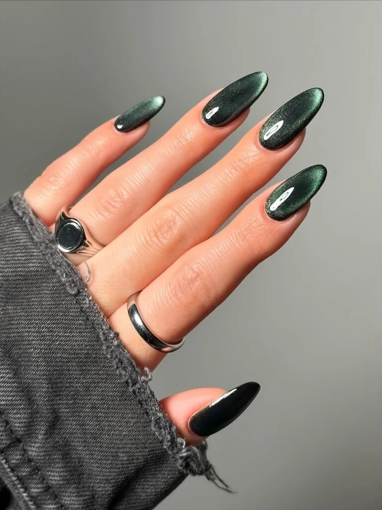 Long almond 2026 autumn nails in deep forest green velvet cat eye with one solid black accent
