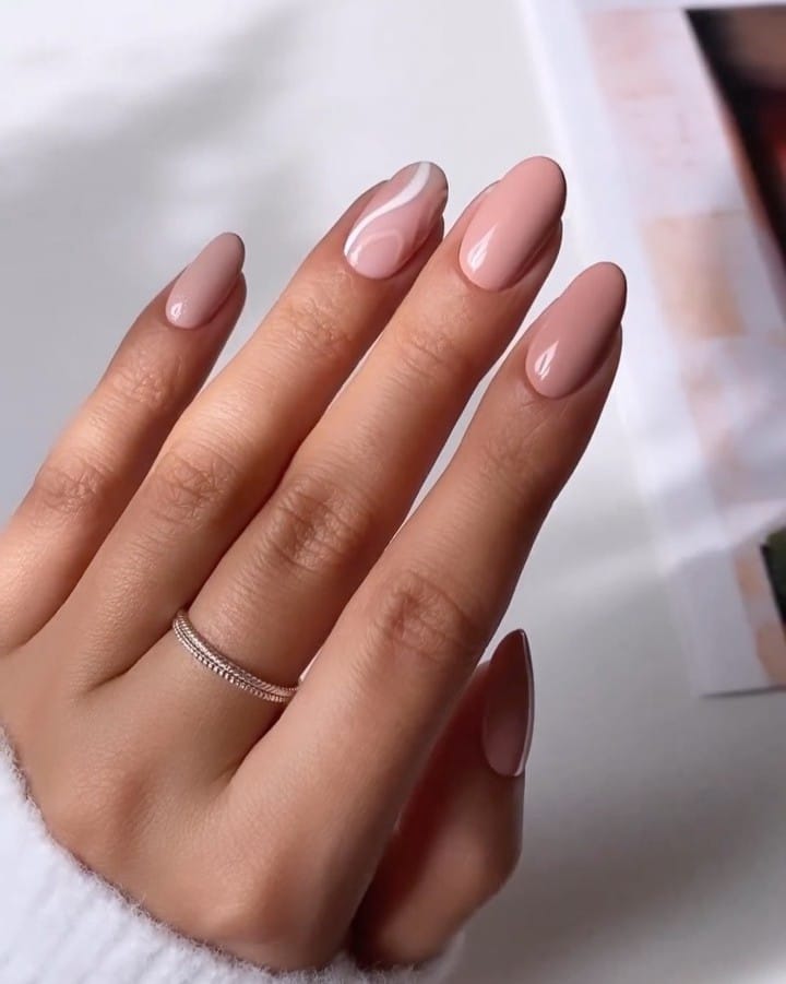 Soft pink nude almond nails with one white abstract wave accent.
