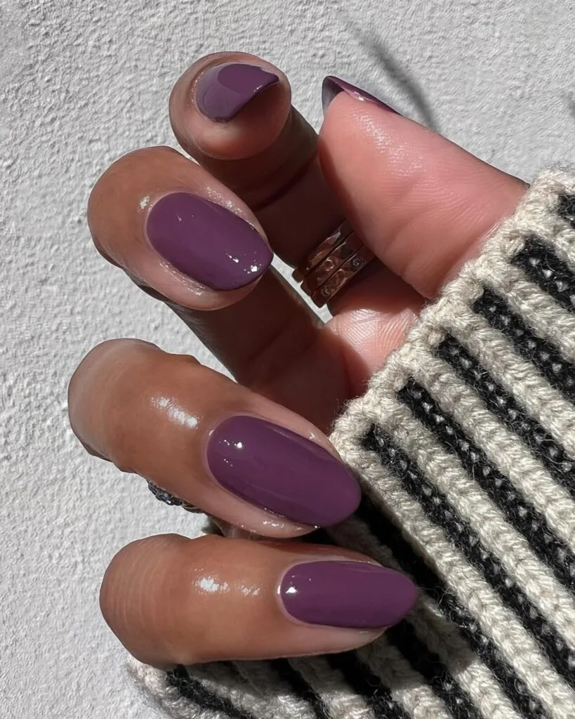 Glossy sugar plum nails on short oval shapes in a muted purple shade for September nails.