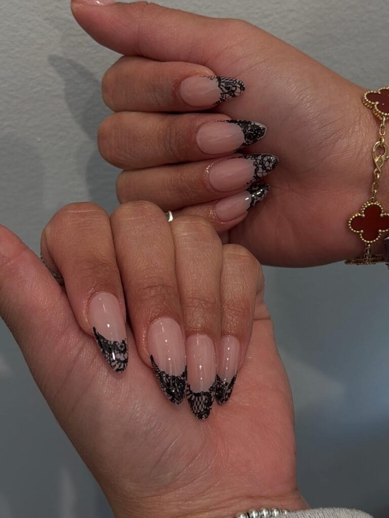 Long almond autumn nail trends with black lace net French tips on a sheer nude base