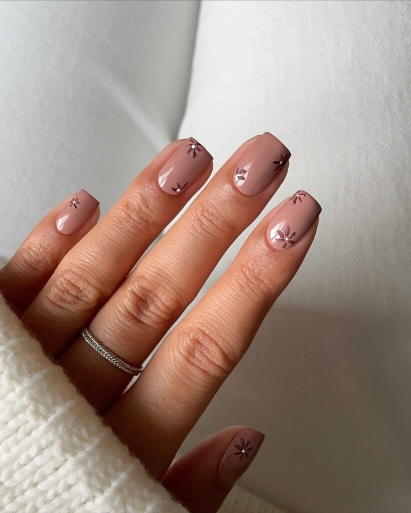 Glossy mauve nude square nails with tiny brown floral accents.

