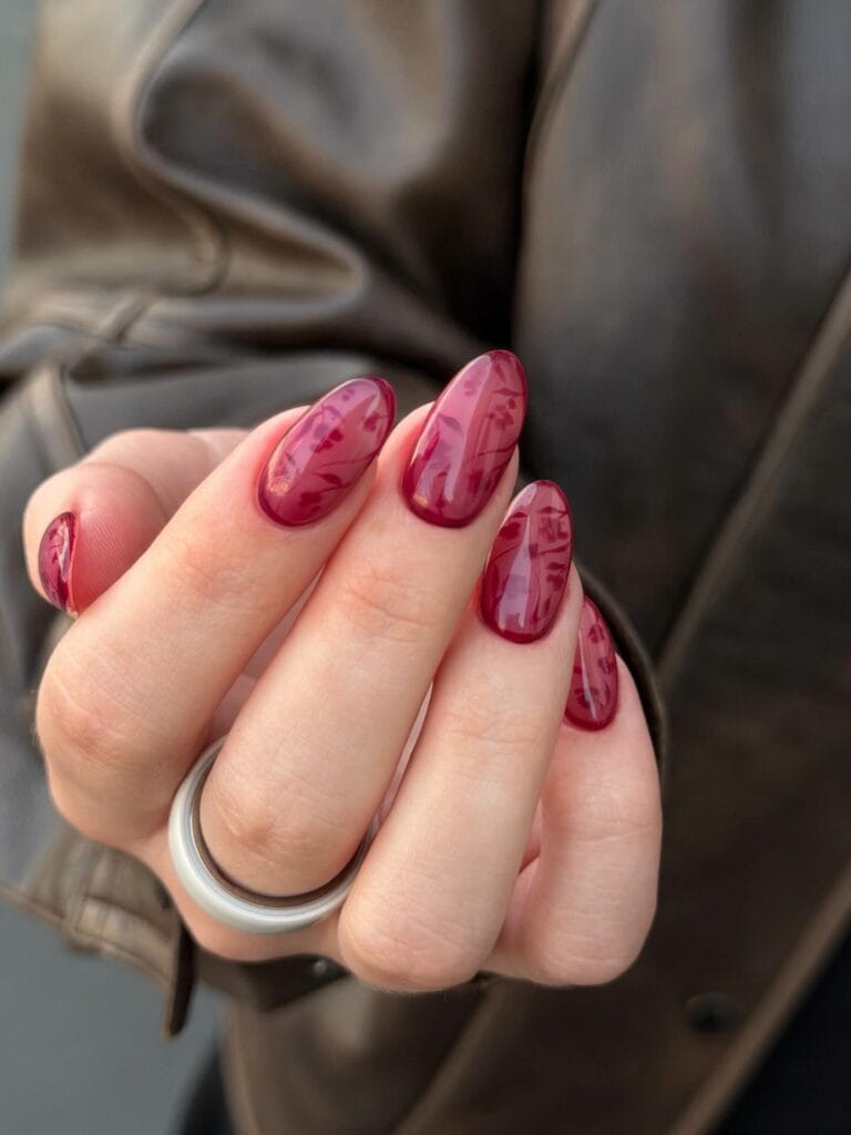 Long almond fall nail trends 2026 in deep wine jelly with a faint botanical silk print