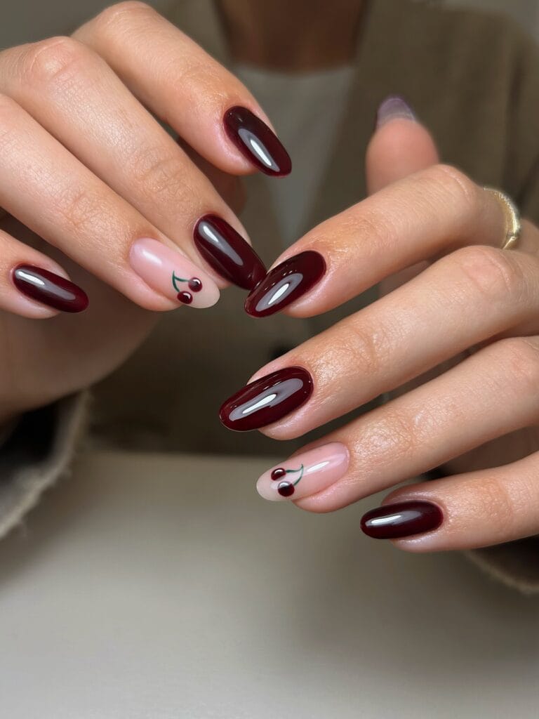 Glossy black cherry oval nails with nude accent nails and tiny cherry art, an autumn nails look.
