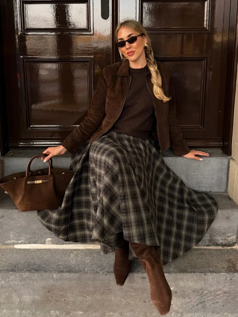 Brown plaid midi skirt with a suede jacket and boots in a layered fall outfit.