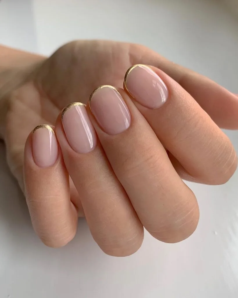Short round 2026 autumn nails in sheer nude with a fine gold foil micro French tip