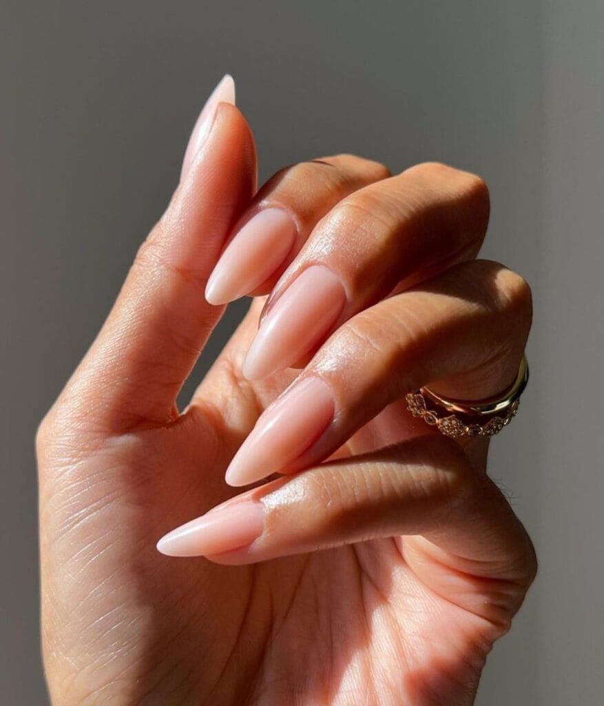 Milky blush nude almond nails with a glossy finish.
