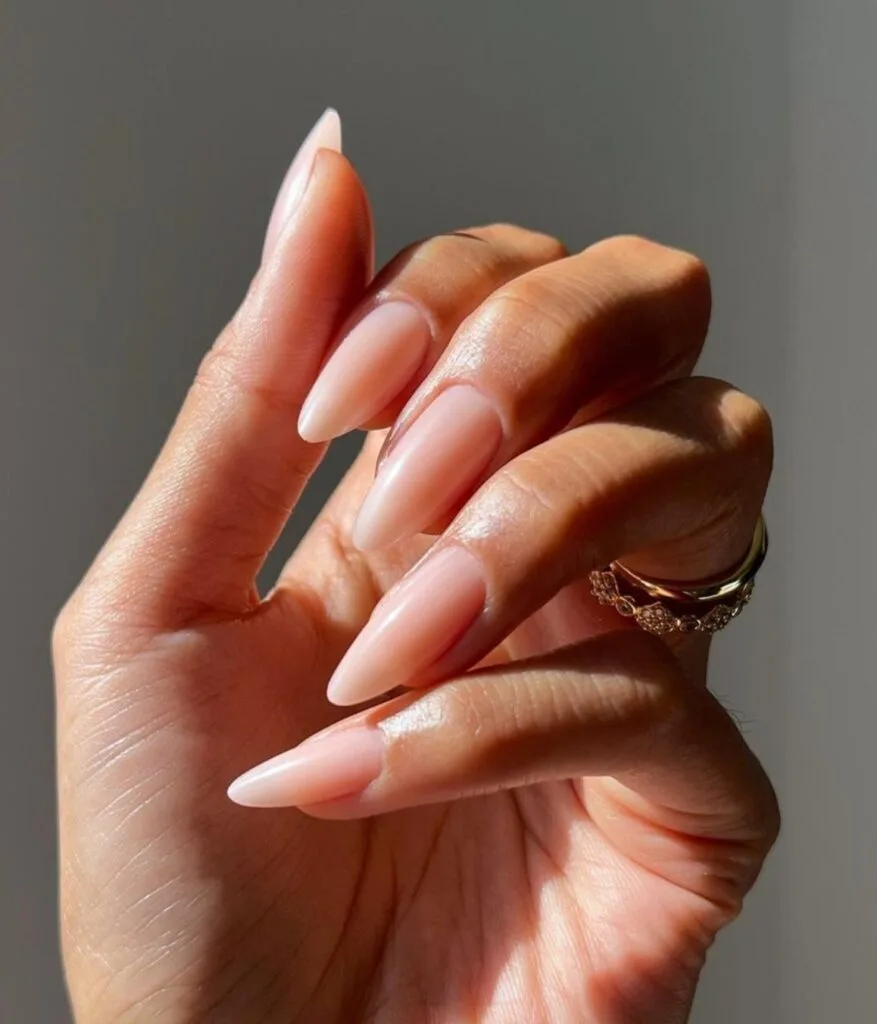 Milky blush nude almond nails with a glossy finish.