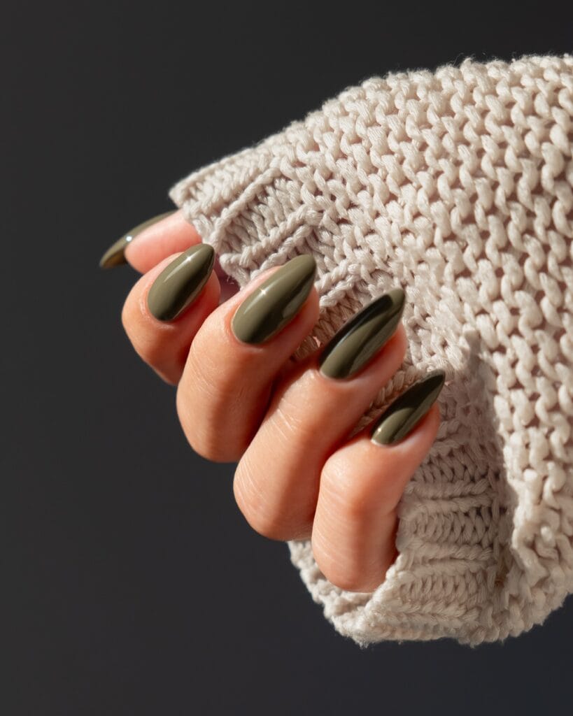 Glossy burnt olive almond nails against a cream knit sweater, fall nail colors.