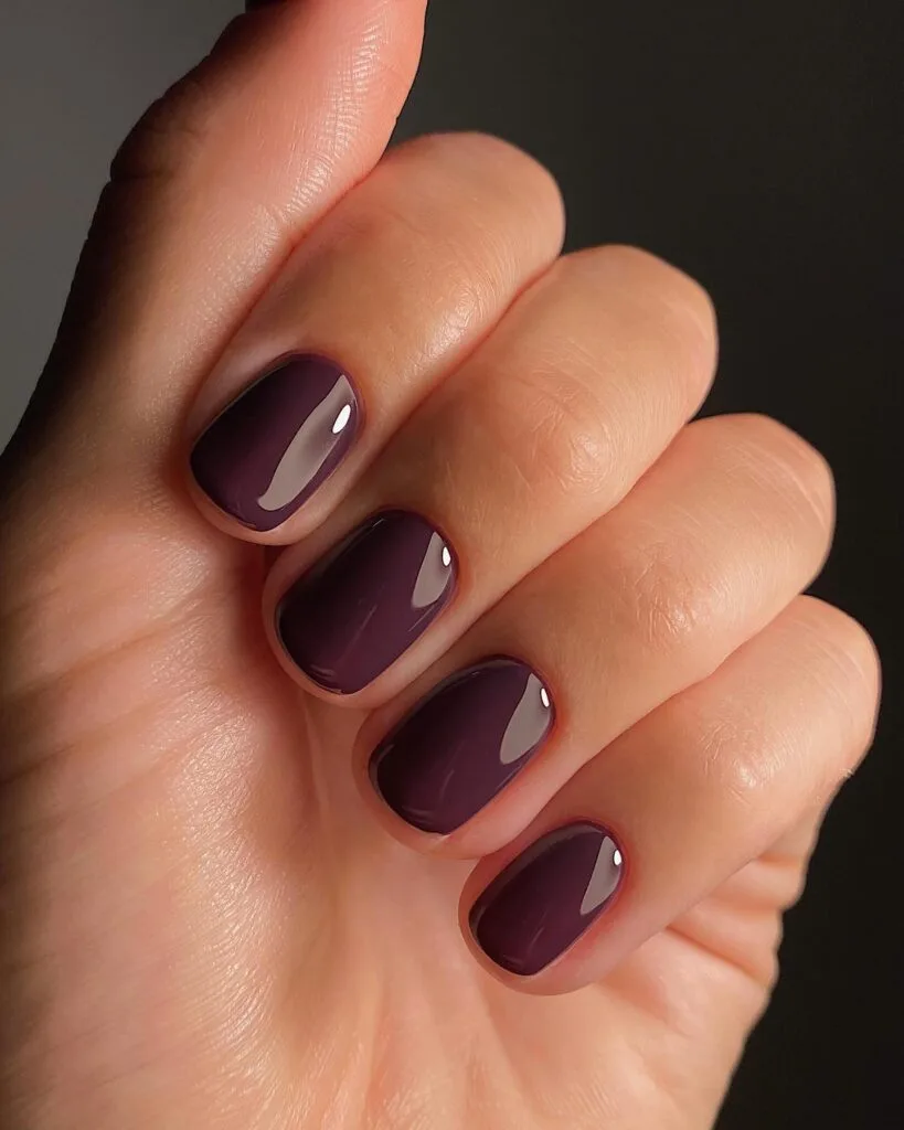 Short square glass-finish nails in deep plum with a wet-look gloss for September nails.