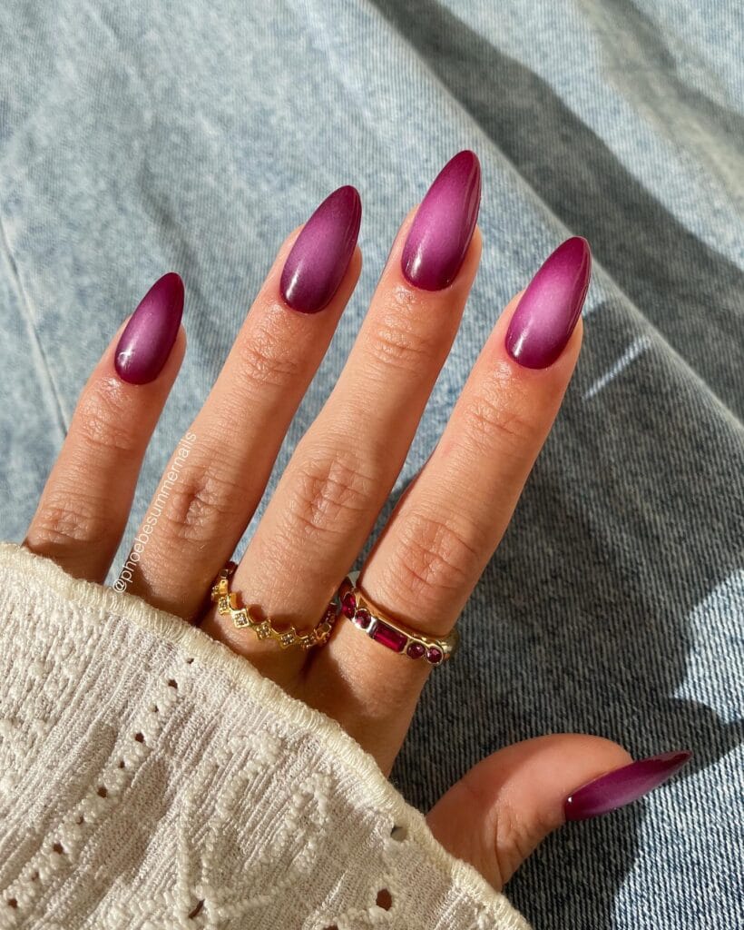 Long almond autumn nail trends in deep berry aura with a soft glowing center