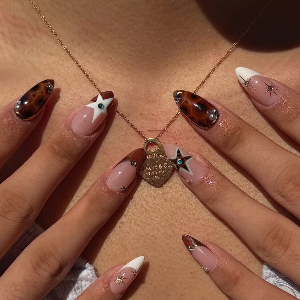 Long almond tortoise nails with tortoiseshell accents, white stars, French tips and tiny gems.
