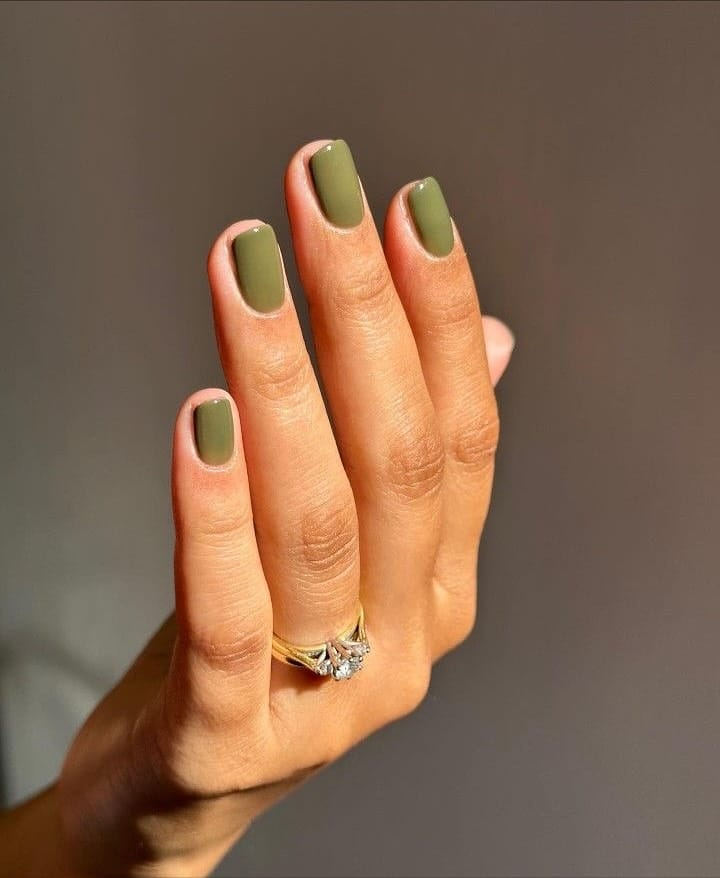 Short square burnt olive nails with a glossy finish in warm sunlight, fall nails inspiration.