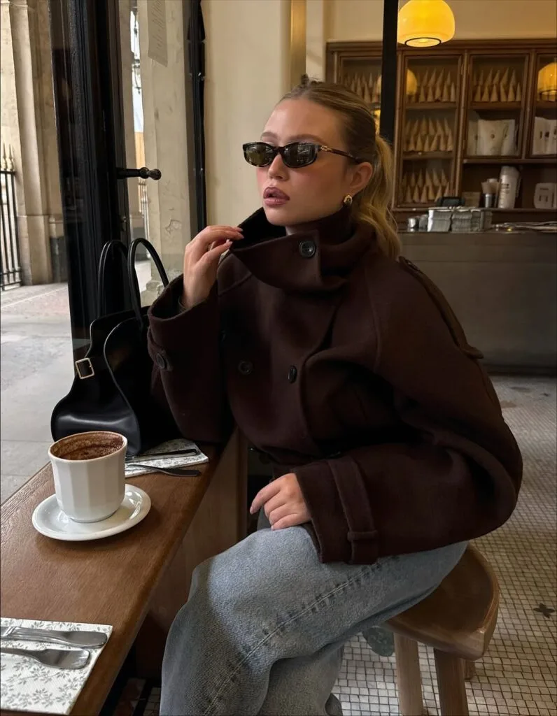 Cropped brown funnel-neck jacket with jeans in a fall 2026 outfit at a café.
