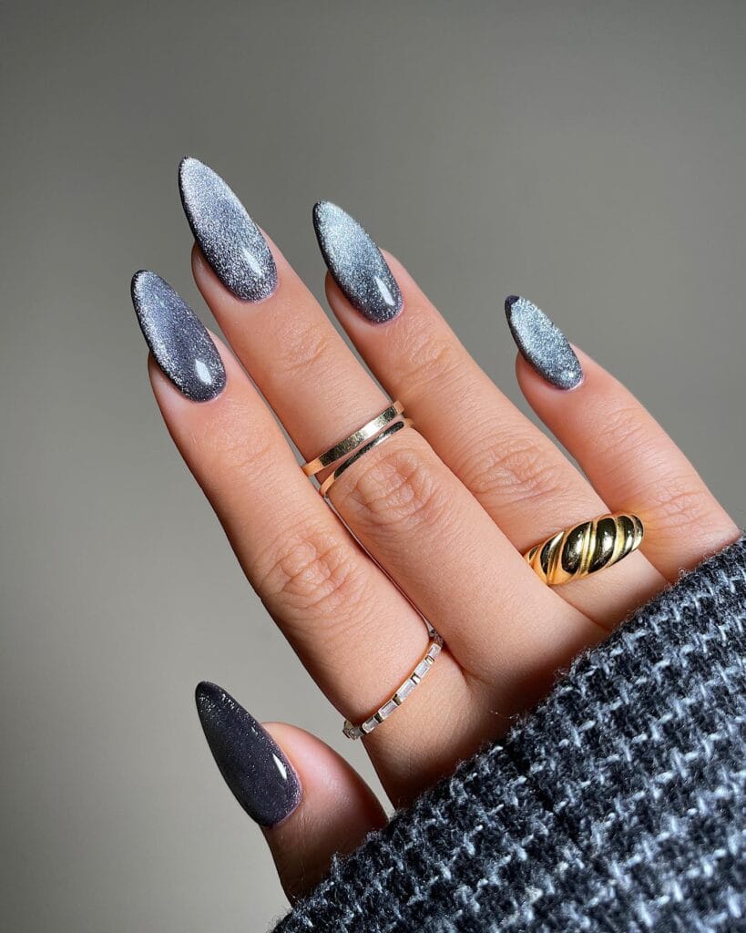 Long almond fall nail trends 2026 in silver gray glitter cat eye with one darker charcoal nail