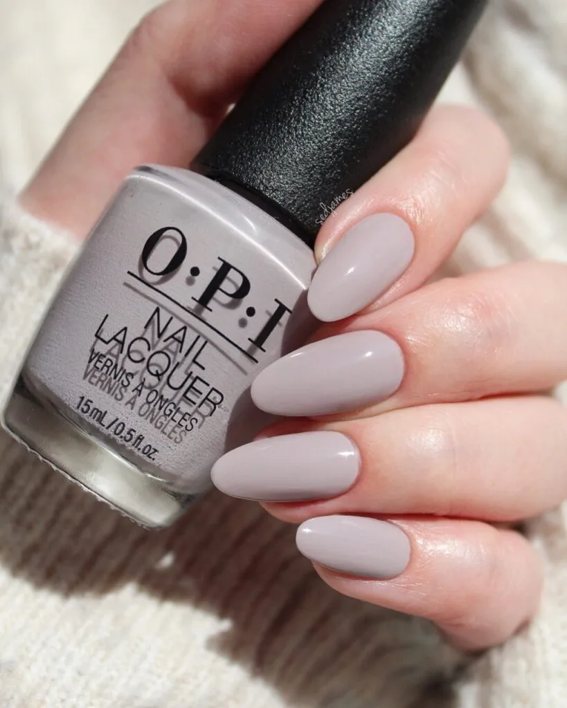 Cool taupe almond nails beside an OPI bottle labeled "O·P·I Nail Lacquer".