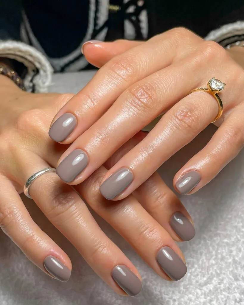 Short rounded cool taupe nails with a glossy gray-beige finish for September nails.