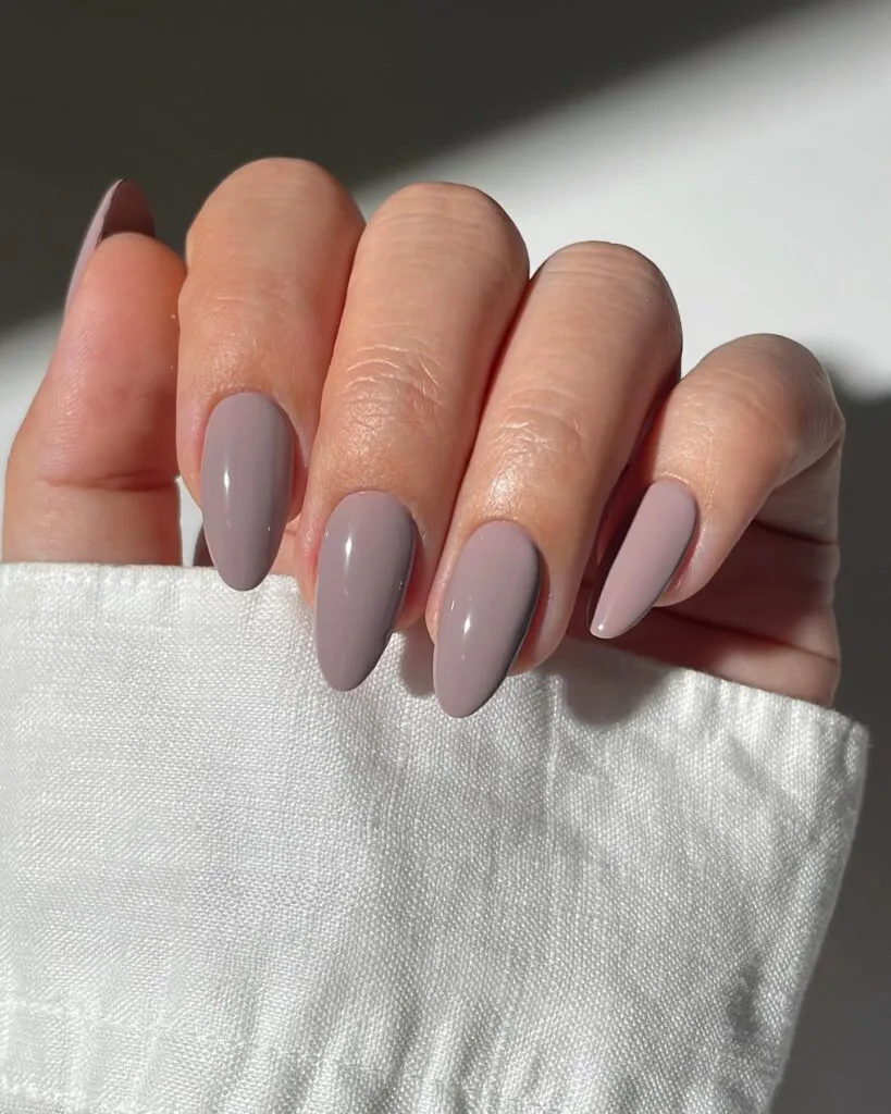 Long almond cool taupe nails with a glossy muted gray finish, an autumn nails look.