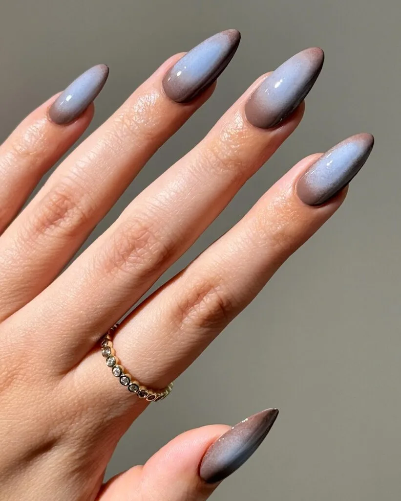 Pale blue fall aura nails with smoky taupe-grey edges and glossy almond shapes.