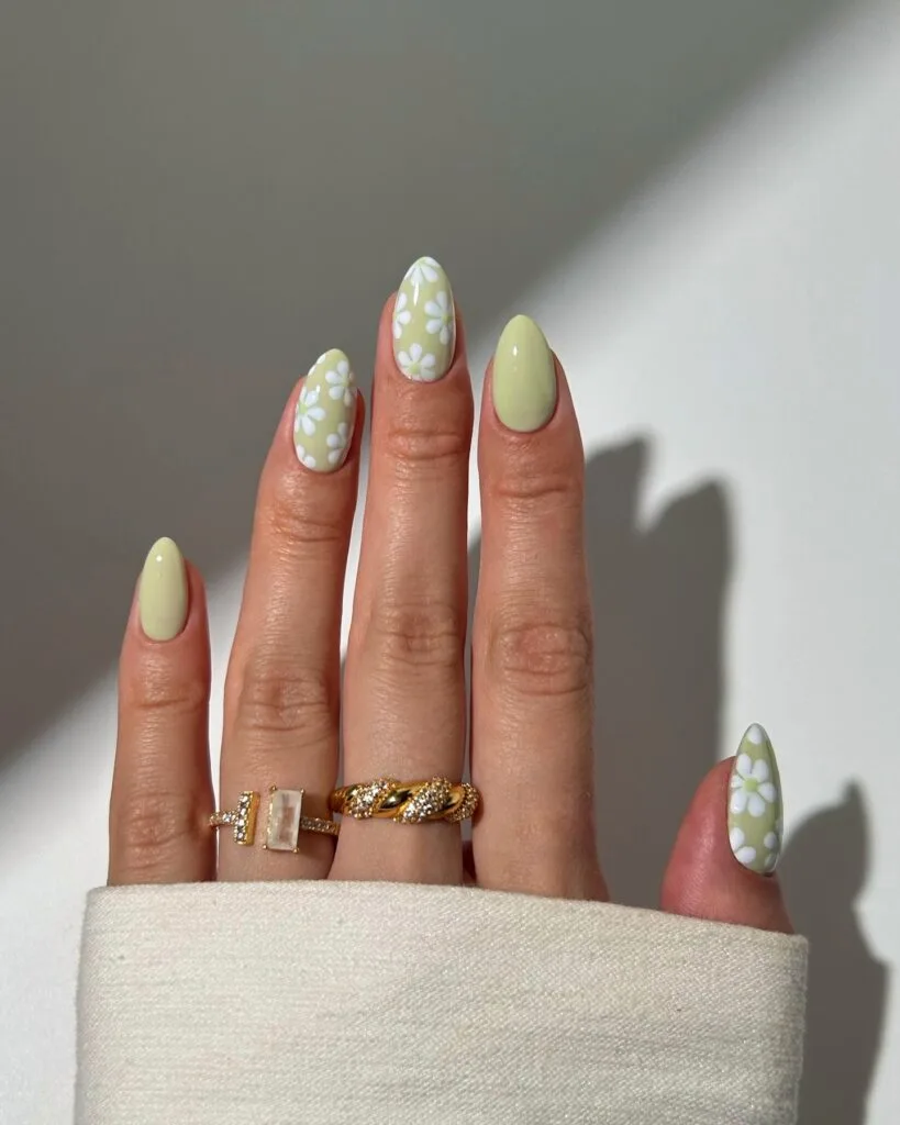 Almond sage green nails with white daisy nail art on three fingers for early fall nails.