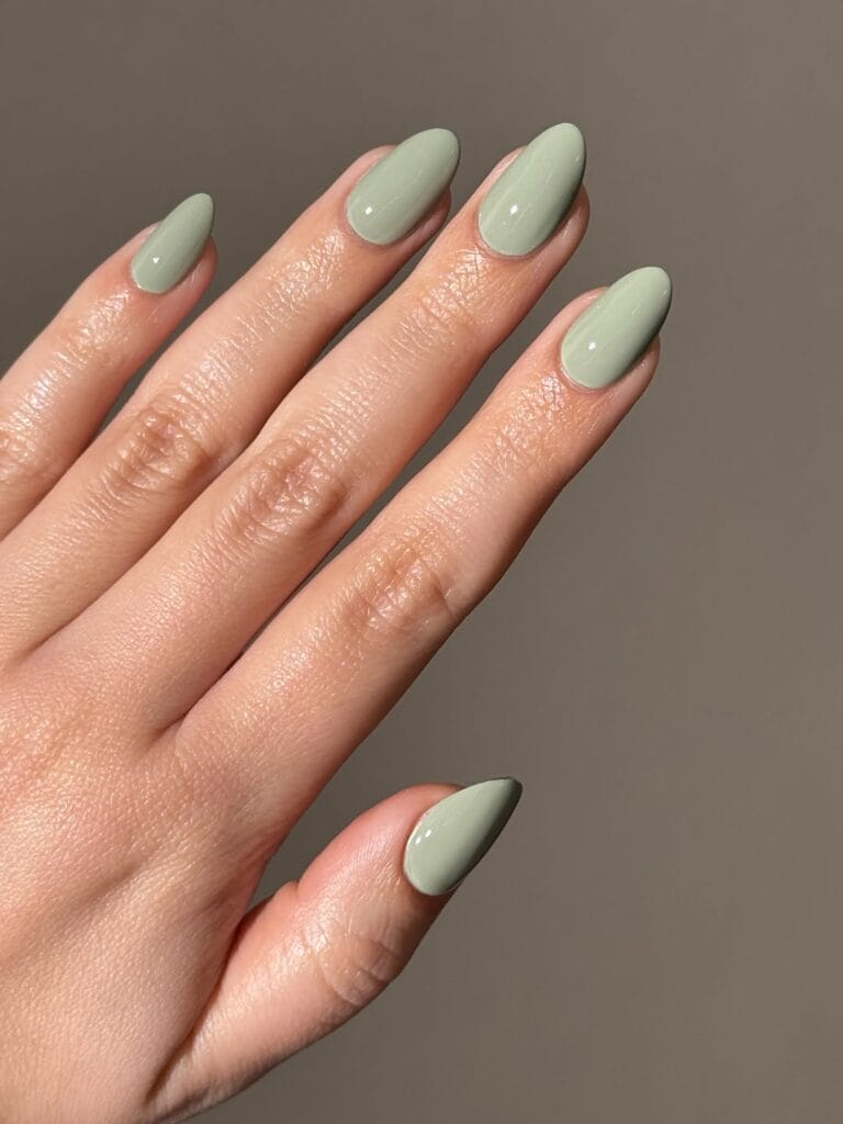 Almond glossy sage green nails in a soft muted shade, an autumn nail colors idea.