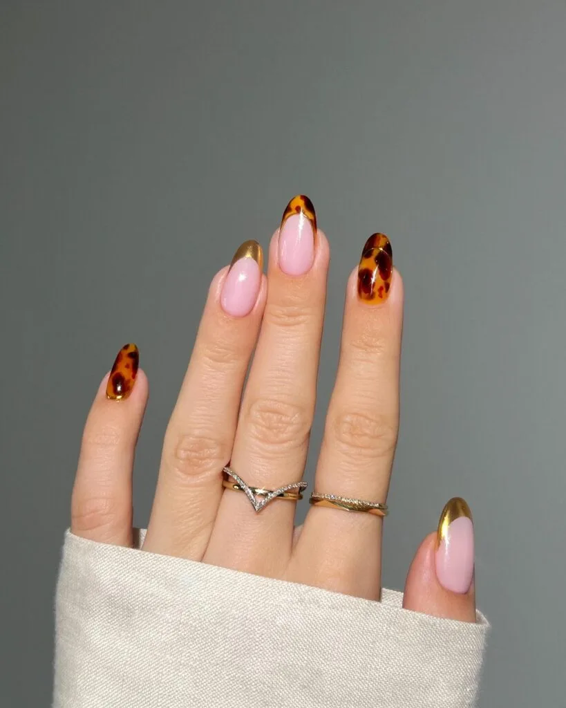 Almond tortoiseshell nails with milky pink, tortoise French tips and metallic gold tips.
